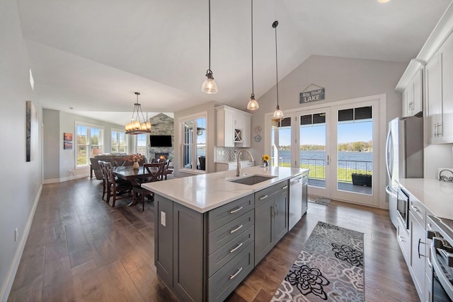 kitchen with gray cabinetry, a sink, white cabinetry, appliances with stainless steel finishes, and vaulted ceiling