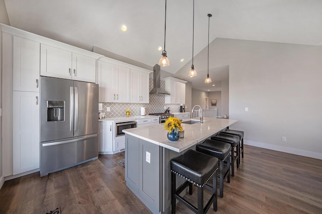 kitchen featuring a sink, dark wood finished floors, white cabinetry, stainless steel appliances, and wall chimney exhaust hood