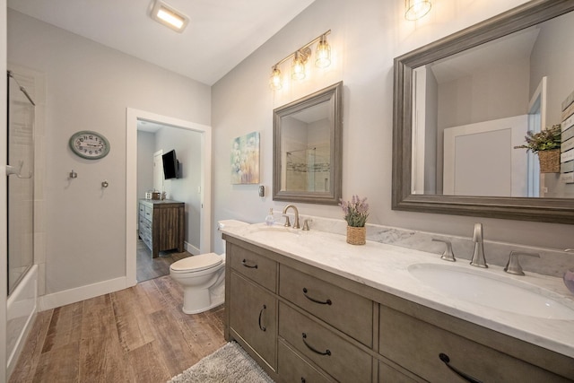 full bath with double vanity, wood finished floors, toilet, and a sink