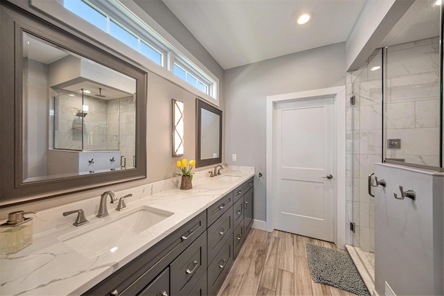 bathroom with double vanity, a stall shower, wood finished floors, and a sink