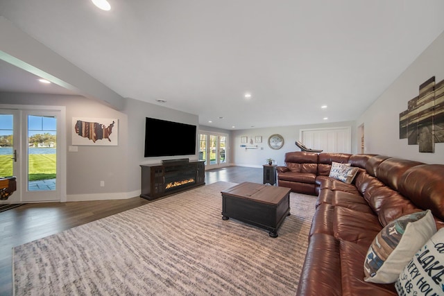 living room featuring a glass covered fireplace, recessed lighting, wood finished floors, and baseboards