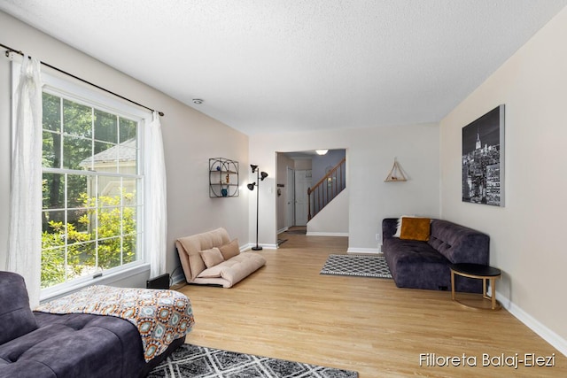 living area featuring stairway, wood finished floors, a wealth of natural light, and a textured ceiling