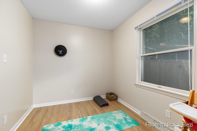 interior space featuring a textured ceiling, baseboards, and wood finished floors