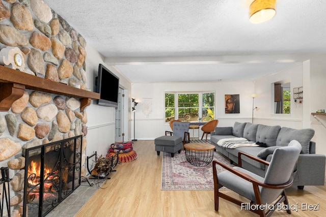 living area with a fireplace, a textured ceiling, and wood finished floors