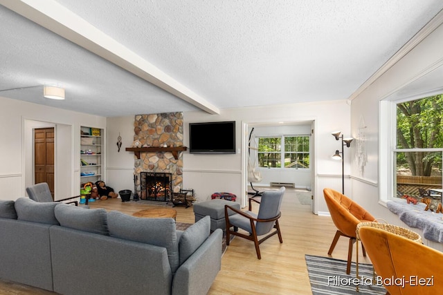 living room featuring beam ceiling, a stone fireplace, light wood-style flooring, a textured ceiling, and a baseboard radiator