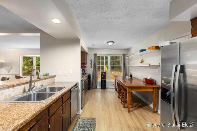 kitchen with light countertops, light wood-type flooring, appliances with stainless steel finishes, a textured ceiling, and a sink