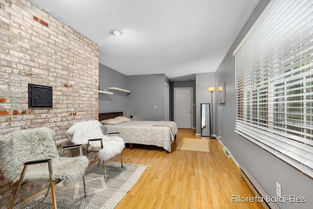 bedroom with visible vents, baseboards, baseboard heating, wood finished floors, and a textured ceiling