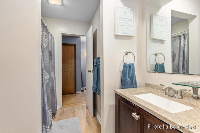 full bath featuring a textured ceiling, vanity, and wood finished floors