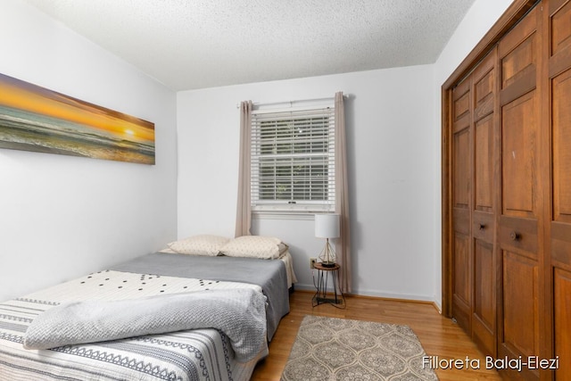 bedroom with a closet, a textured ceiling, and light wood finished floors