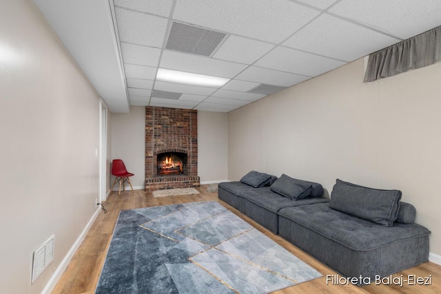 living area with a brick fireplace, wood finished floors, and visible vents