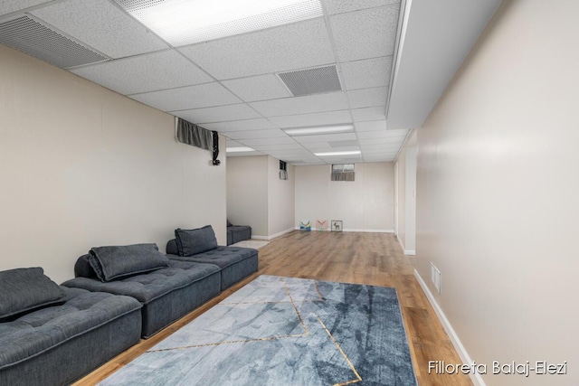 living area featuring wood finished floors, visible vents, a drop ceiling, and baseboards