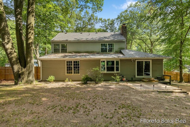 rear view of house with a patio, a chimney, and fence