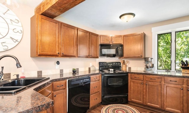 kitchen with a sink, brown cabinets, black appliances, and dark wood finished floors