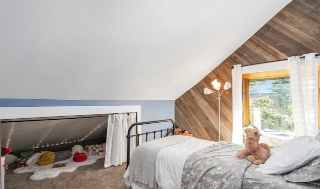 bedroom with vaulted ceiling, wood walls, and carpet floors