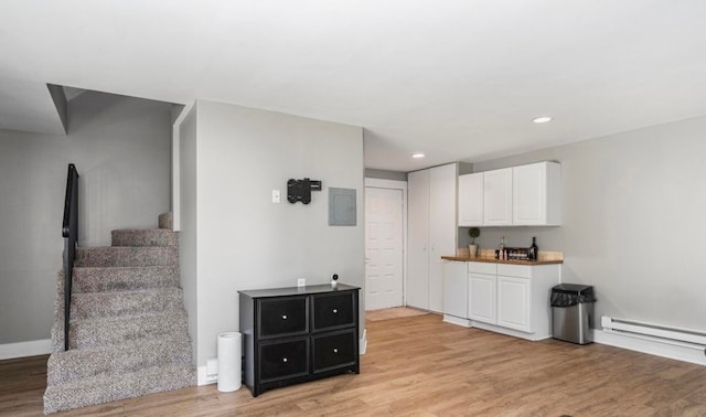 kitchen featuring a baseboard radiator, electric panel, recessed lighting, white cabinetry, and light wood-type flooring