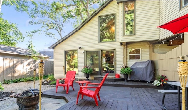 wooden deck featuring grilling area, a fire pit, and fence