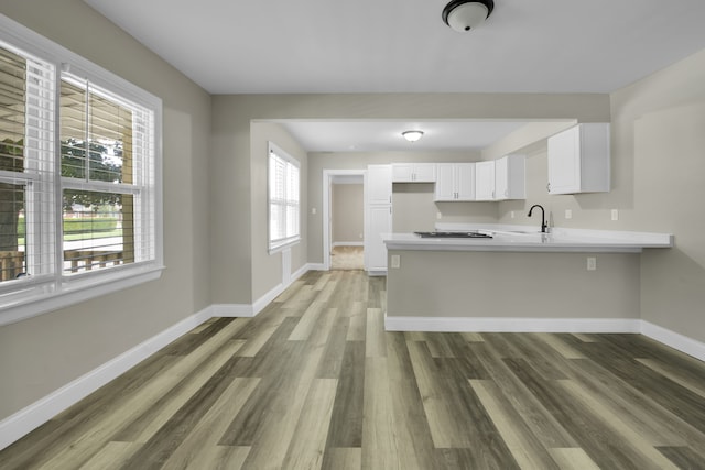 kitchen with a peninsula, light countertops, baseboards, and a sink