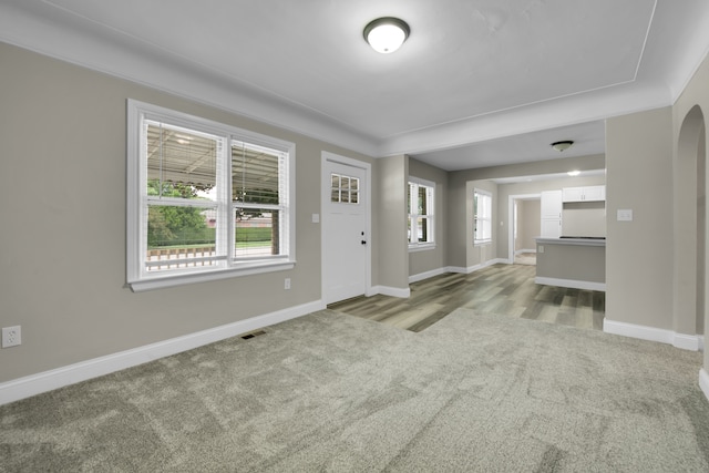 entryway featuring visible vents, arched walkways, light colored carpet, and baseboards