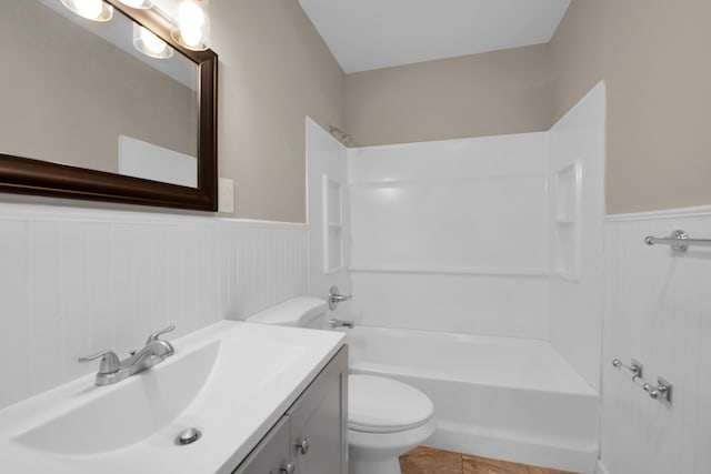 full bath featuring washtub / shower combination, vanity, toilet, and wainscoting