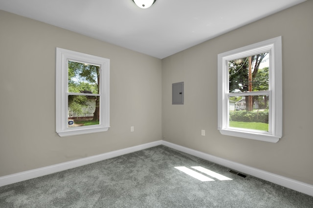 carpeted spare room featuring electric panel, baseboards, and visible vents