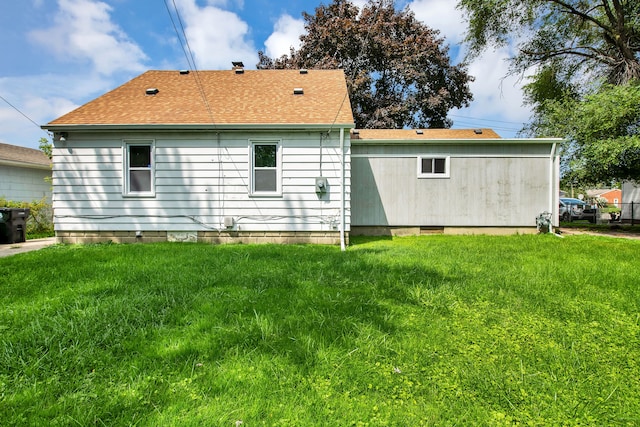 back of property with crawl space, a lawn, and roof with shingles