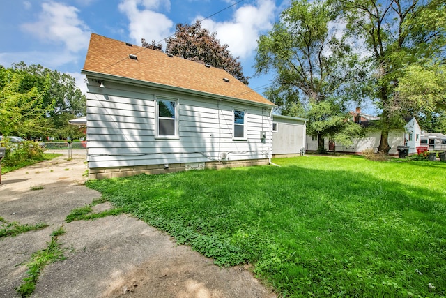 exterior space featuring a lawn, roof with shingles, and fence