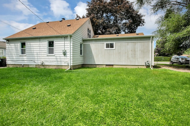 view of side of home with a lawn and a shingled roof