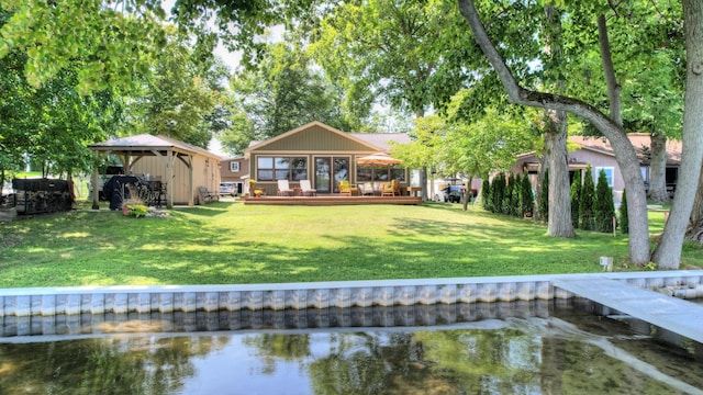 rear view of property with a deck with water view and a yard