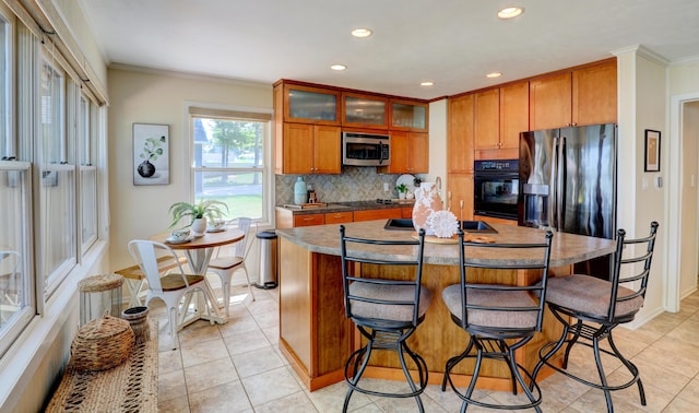 kitchen featuring black appliances, ornamental molding, backsplash, brown cabinetry, and glass insert cabinets