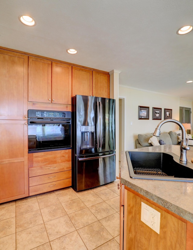 kitchen featuring black appliances, a sink, open floor plan, light countertops, and light tile patterned floors