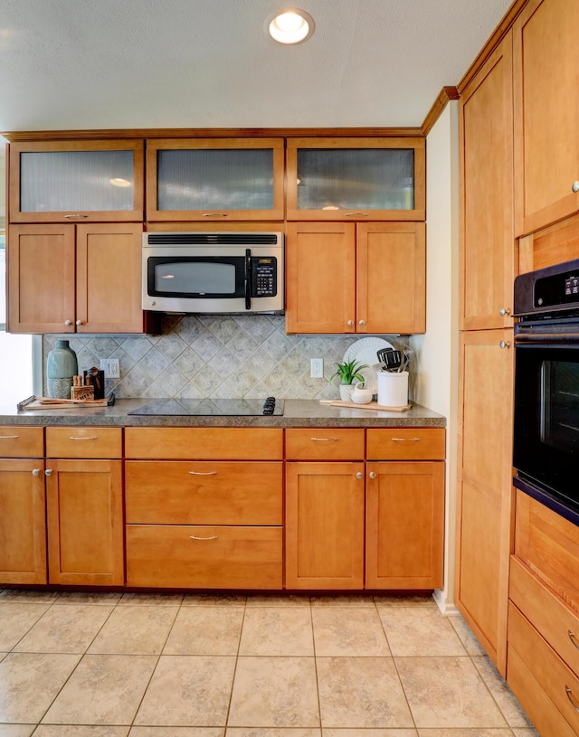 kitchen featuring brown cabinetry, decorative backsplash, and black appliances