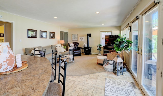 dining room featuring visible vents, a wood stove, light tile patterned flooring, recessed lighting, and crown molding