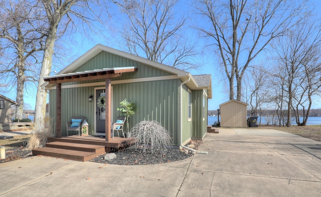 view of front facade with an outdoor structure, a storage unit, covered porch, and a water view