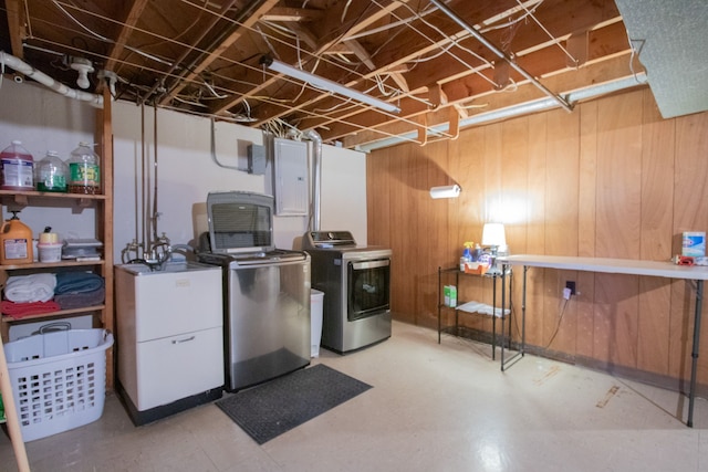 unfinished basement featuring wooden walls, electric panel, and washer and clothes dryer