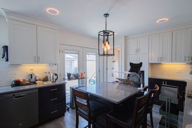 kitchen with a kitchen bar, backsplash, white cabinetry, light stone countertops, and dishwasher