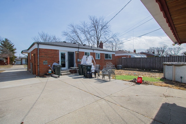 back of property with brick siding, fence, cooling unit, a chimney, and a patio area