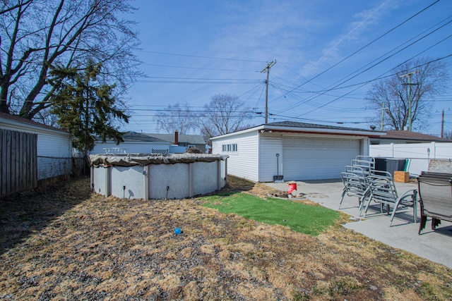 view of yard with a garage, an outbuilding, a covered pool, and fence