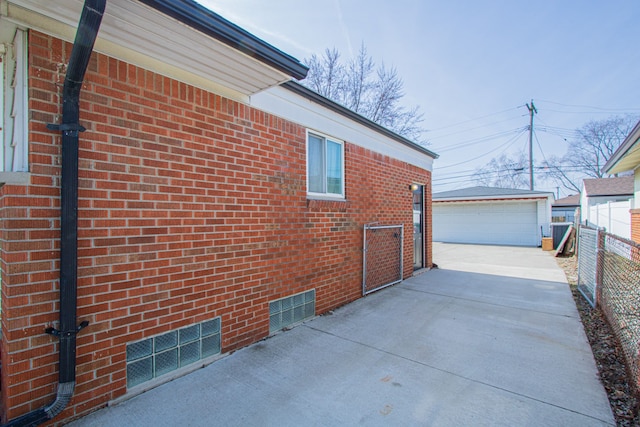 view of property exterior with brick siding, an outbuilding, a garage, and fence