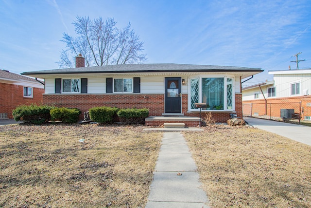 view of front facade featuring brick siding, central AC, a chimney, and fence