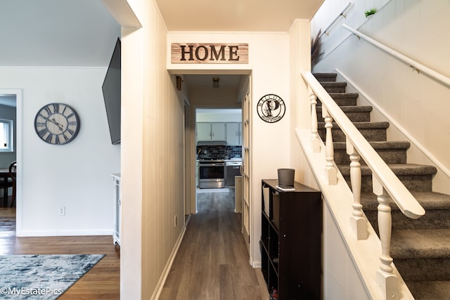 corridor with stairs, dark wood-type flooring, and baseboards