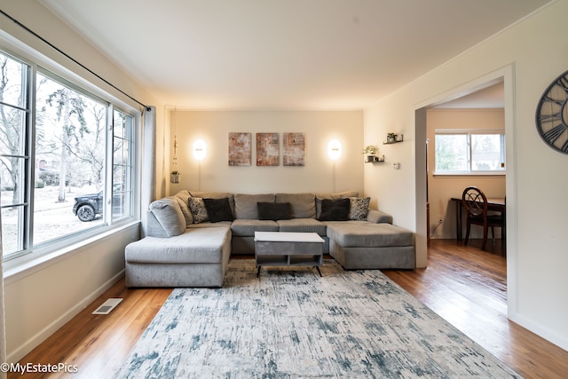 living area with wood finished floors, visible vents, and baseboards