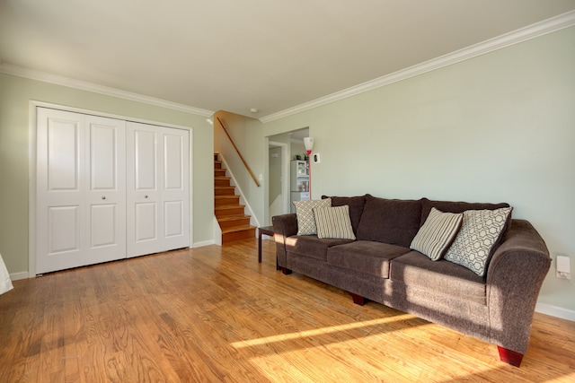 living area featuring stairway, wood finished floors, baseboards, and ornamental molding