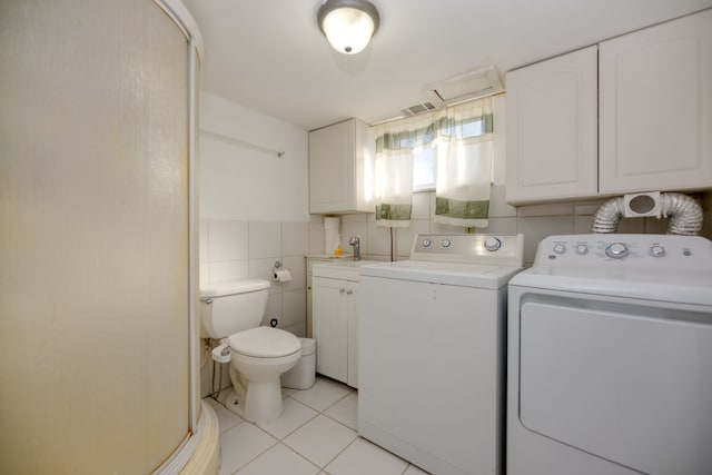 laundry area with visible vents, laundry area, light tile patterned flooring, separate washer and dryer, and tile walls