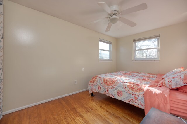 bedroom with ceiling fan, baseboards, and wood finished floors