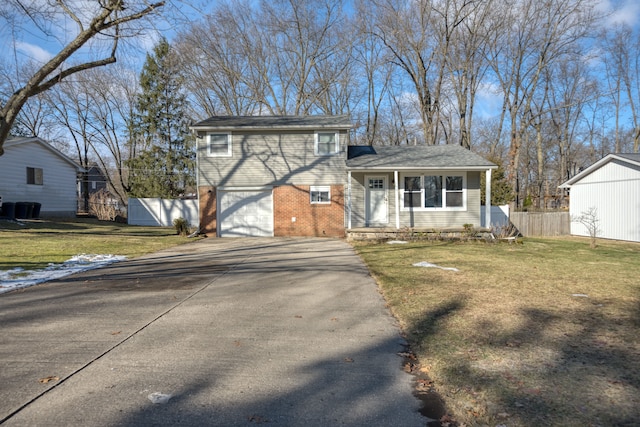 tri-level home with a front lawn, brick siding, driveway, and fence