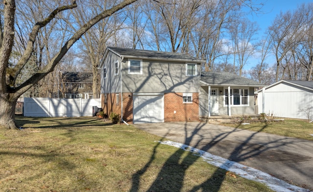 tri-level home with driveway, a porch, fence, a front yard, and brick siding