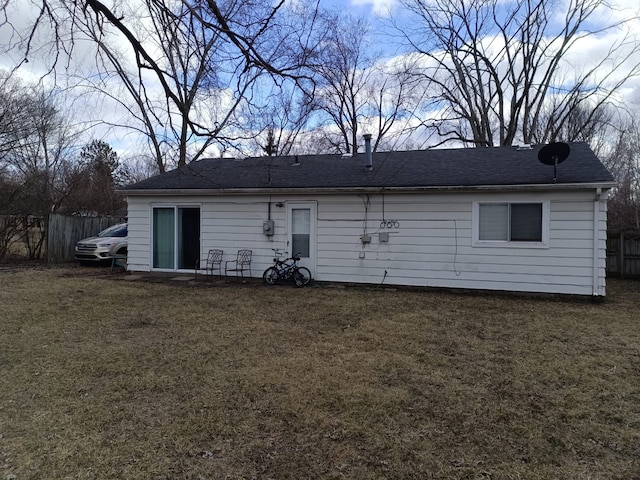 back of property featuring a lawn and fence