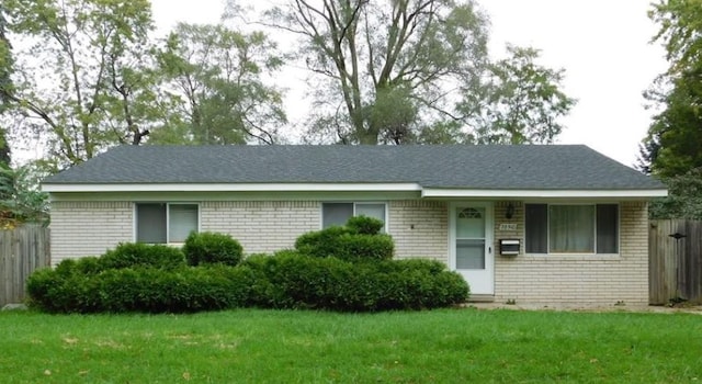 ranch-style home with a front yard, fence, and brick siding