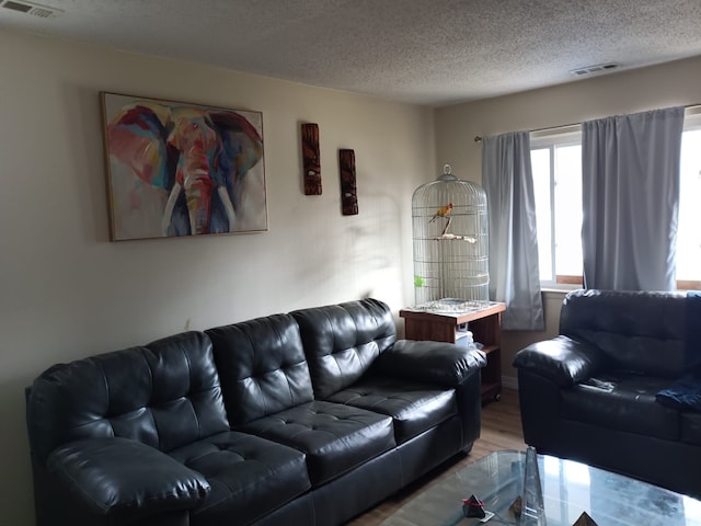 living room featuring visible vents, a textured ceiling, and light wood-style flooring