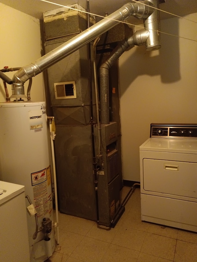 utility room with water heater, visible vents, and washer / clothes dryer